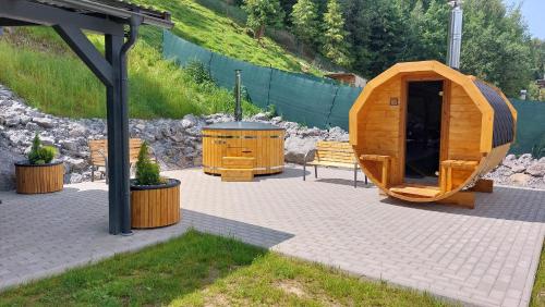 a wooden iguana house with a grill and a bench at Rezort pod Roháčmi in Vitanová