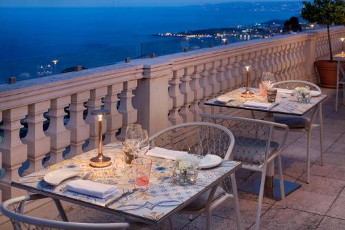 two tables with wine glasses on top of a balcony at NH Collection Taormina in Taormina