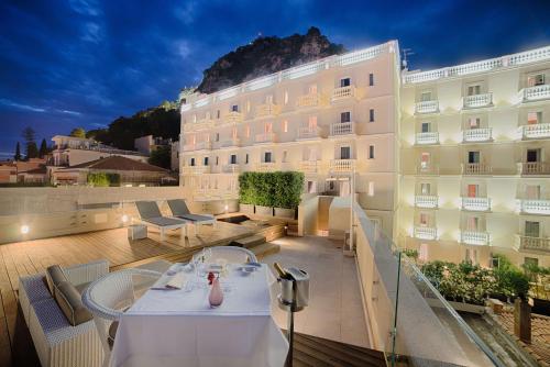 a hotel with tables and chairs on a balcony at NH Collection Taormina in Taormina