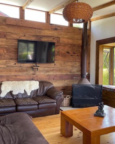 a living room with a couch and a tv on a wall at Cabañas y Lodges de Playa Ritoque RITOKAZO in Quintero