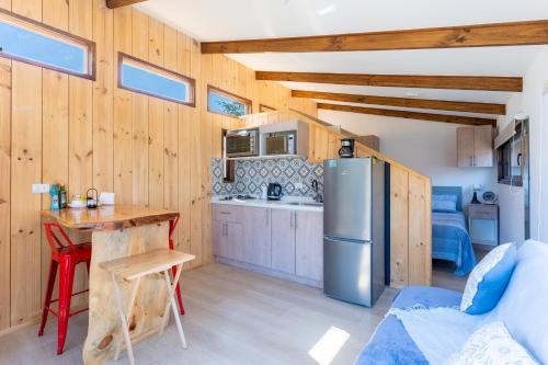 a kitchen with wooden walls and a table and a refrigerator at Cabañas y Lodges de Playa Ritoque RITOKAZO in Quintero