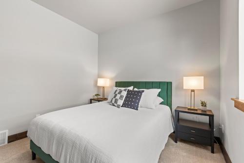 a bedroom with a white bed and two night stands with lamps at Spacious 4-bedroom Townhome New Black Rock in Kamas