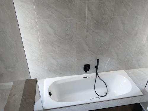 Una bañera blanca con un cable negro enchufado. en Arum Cove Bloubergstrand, en Cape Town