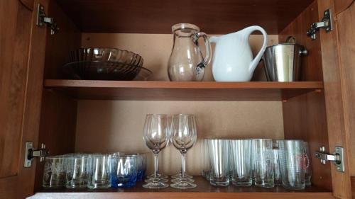 a shelf with wine glasses and a pitcher and vases at Стаи за гости Роса in Rosno