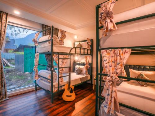 a room with three bunk beds with a guitar at Moustache Hostel Pahalgam in Pahalgām