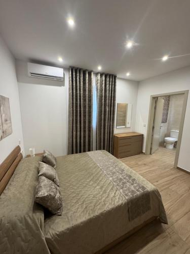 a bedroom with a large bed and a bathroom at Varka Holiday Apartment - Modern Family Friendly and Accessible for All in Marsaxlokk