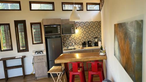a small kitchen with a wooden table and red stools at Cabañas y Lodges de Playa Ritoque RITOKAZO in Quintero