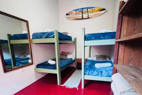 a room with three bunk beds and a mirror at Pousada da Rosa in Ilhabela