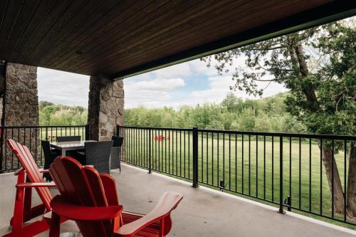 a screened in porch with red chairs and a table at 2 bedroom suite with views of Sommets St-Sauveur in Saint-Sauveur-des-Monts