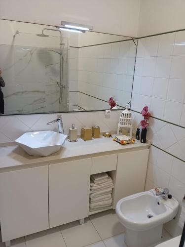 a bathroom with a sink and a toilet and a mirror at Apartamento Praia de Santa Cruz - Casa Mar in Silveira
