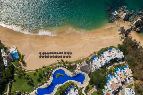 eine Luftansicht auf einen Strand mit Eigentumswohnungen und das Meer in der Unterkunft Beautiful Condo in a great Beach Hotel complex in Bahías de Huatulco