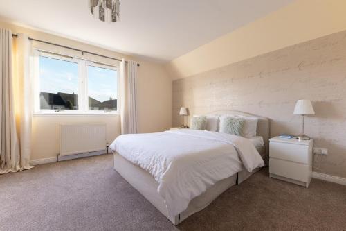 a white bedroom with a large bed and a window at Lochnomore - A Luxury Home With Magnificent Views in Nairn