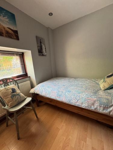 a bedroom with a bed and a chair and a window at Nanternis Farm in New Quay