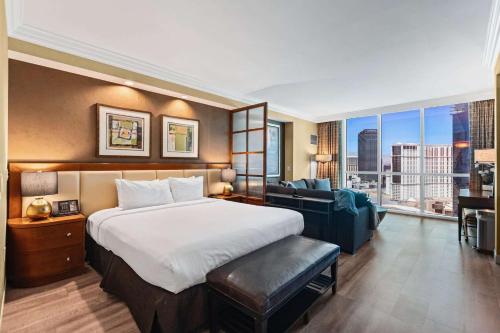 a hotel room with a bed and a couch at No Resort Fee Strip View Suites+ Free Valet + Pool in Las Vegas