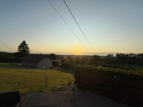 un coucher de soleil sur un champ avec une maison au premier plan dans l'établissement Studio villa vue lac, à Marin