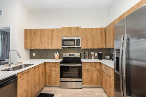 a kitchen with wooden cabinets and stainless steel appliances at Orlando 2BR Retreat 3 Beds Near Disney&Universal in Orlando