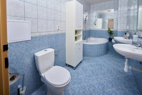 Un baño con dos lavabos, un inodoro y una bañera. en Skyline Penthouse with Terrace, en Bratislava