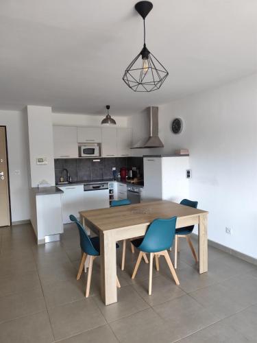 une cuisine avec une table en bois et des chaises bleues dans l'établissement T2 tout équipé avec une belle terrasse face mer, à San-Nicolao