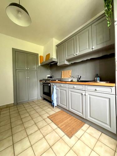 une cuisine avec des armoires blanches et un sol carrelé dans l'établissement Ty Rorabeach - Vue port, familiale et proche des plages, à Plougastel-Daoulas