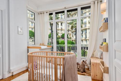 Cette chambre comprend un lit bébé et de grandes fenêtres. dans l'établissement Sumptuous Art Deco Apartment - 6 People, à Nice