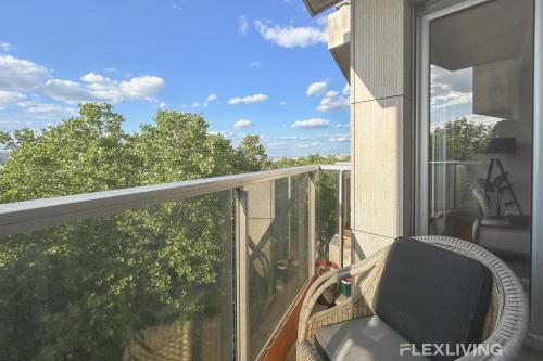une chaise assise sur un balcon donnant sur la fenêtre dans l'établissement Spacious 2-Bedroom Apartment with Balcony Steps from Buttes-Chaumont Park, à Paris