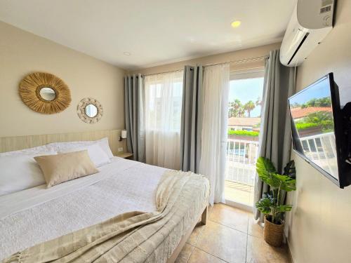 Un dormitorio con una cama y una ventana grande. en Rooi Santo Residence, en Palm-Eagle Beach