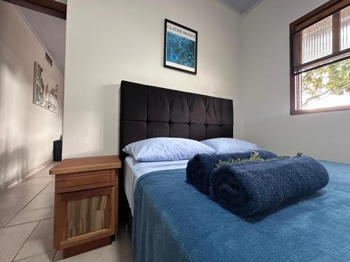 a bedroom with a large bed with a blue blanket at Villa Cavaliere in Palhoça