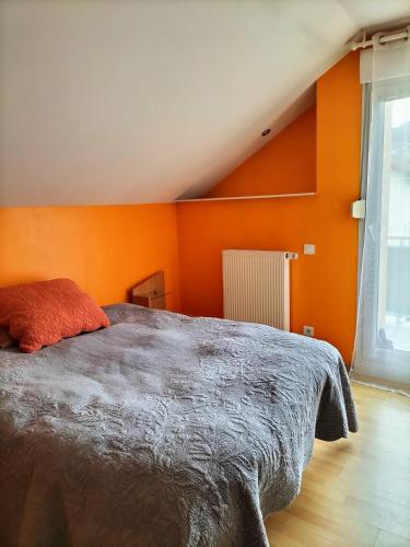 - une chambre avec des murs orange et un grand lit dans l'établissement Maison le Trèfle Argenté, à Gérardmer