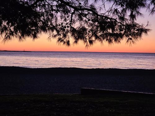 a sunset over the ocean with a bench on the beach at Relax Apartments Grazia in Funtana