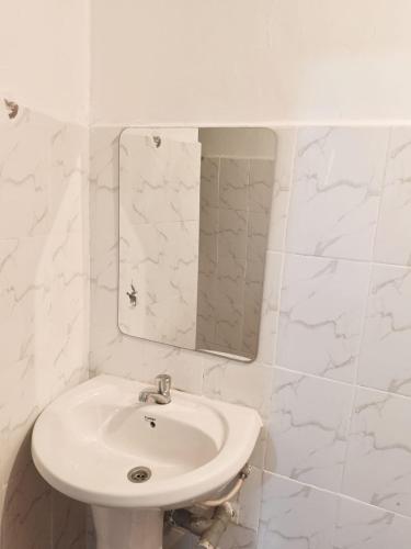 a white bathroom with a sink and a mirror at Modern Stay Ruaka in Ruaka