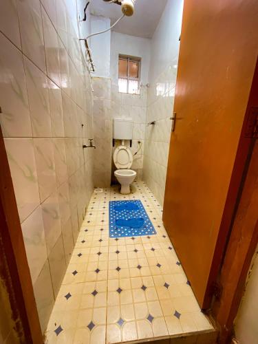 a bathroom with a toilet and a blue tile floor at Modern Stay Ruaka in Ruaka