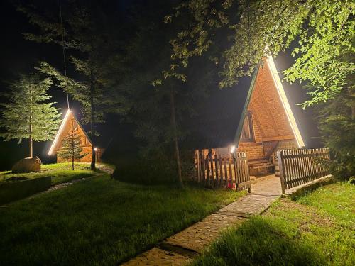 a log cabin at night with a fence and lights at Etno selo BISTROVO in Vitez