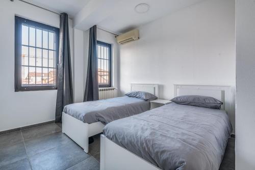 two beds in a room with two windows at three-room apartment with terrace Free Wifi in Bareggio