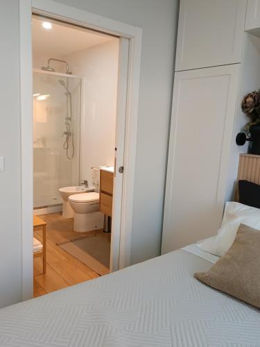 a bedroom with a white bed and a bathroom at Cantinho das Quintãs in Viseu