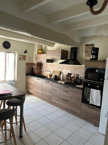 une grande cuisine avec des placards en bois et une table dans l'établissement Romarin, à Mirabel-aux-Baronnies