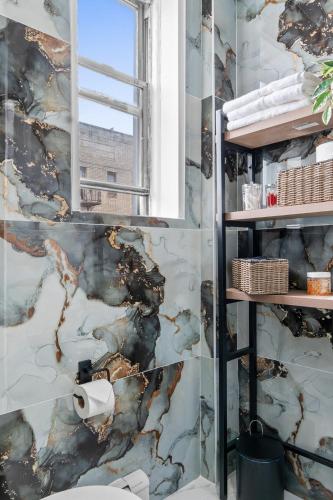 a bathroom with a marble wall at Style & Comfort 3 Rooms 15 min from NYC in West New York