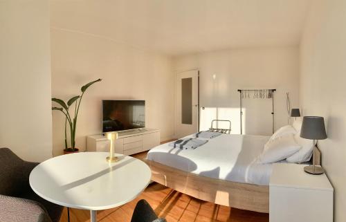 une chambre blanche avec un grand lit et une table dans l'établissement Charming 25m2 studio with panoramic view, à Neuilly-sur-Seine