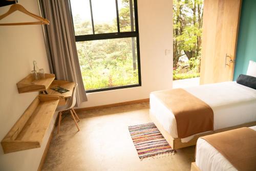 a bedroom with a bed and a desk and a window at Hotel con Corazon Monteverde in Monteverde Costa Rica