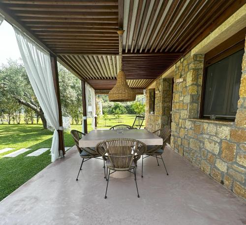 a table and chairs on a patio with a stone wall at Fillis House in Vourvourou