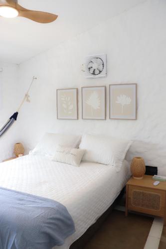 a white bed with three pictures on the wall at Serenity by the Sea in Juan de Acosta