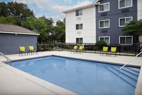 a swimming pool with chairs and a building at Candlewood Suites Jacksonville Southpoint in Jacksonville