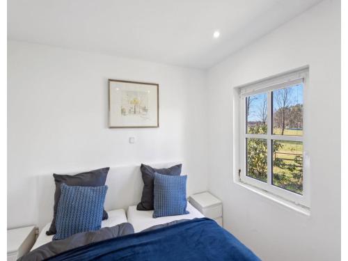a white bedroom with a bed and a window at Ferienhaus, Schneverdingen in Schneverdingen