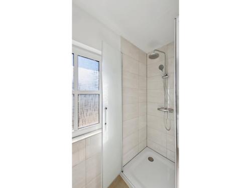 a white bathroom with a shower and a window at Moderne Wohnung mit Terrasse in Schneverdingen