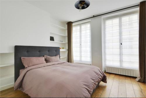 une chambre avec un grand lit et deux fenêtres dans l'établissement Luxury apartment in prestigious Le Marais - Top Location, à Paris