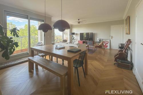 une salle à manger avec une table et un salon dans l'établissement Spacious 2-Bedroom Apartment with Balcony Steps from Buttes-Chaumont Park, à Paris