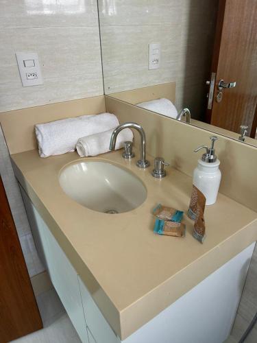 a bathroom counter with a sink and a mirror at Apartamento Praça Inconfidência Bom Despacho in Bom Despacho