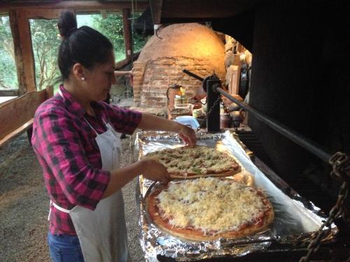 a woman is making two pizzas in an oven at Barraco Lodge in Puelo