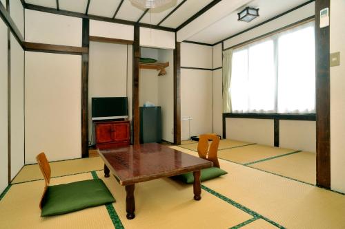 a living room with a wooden table and chairs at Ryokan Seifuso in Matsumoto