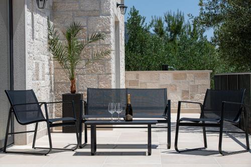 three chairs and a table with a bottle and glasses at Villa Olea Lux Bol in Bol