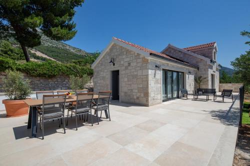 a patio with a table and chairs and a building at Villa Olea Lux Bol in Bol